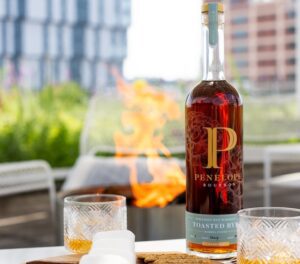 Penelope Tasted Rye Bottle featured on an outdoor table next to two rocks glasses on a sunny day